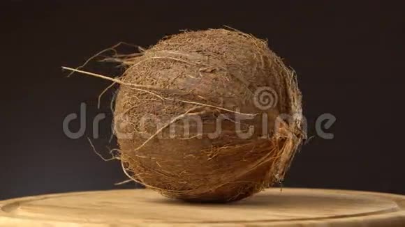 成熟的热带椰子在黑色背景的木桌上旋转热带水果可循环视频的预览图