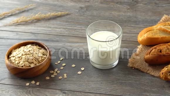 碗里的燕麦片一杯牛奶和一张乡村木桌上的新鲜自制面包视频的预览图