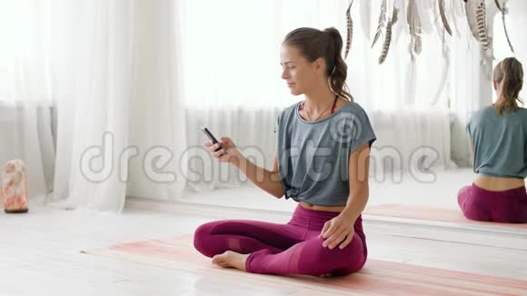 在瑜伽工作室有智能手机的女人视频的预览图
