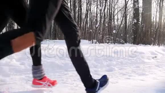 冬季森林在清晨的树林里年轻的男女在小径上奔跑视频的预览图