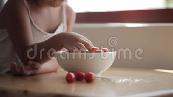小女孩坐在桌边吃樱桃番茄视频的预览图