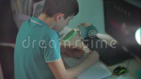 男生写作业少年男生看社交媒体教育网络视频视频的预览图