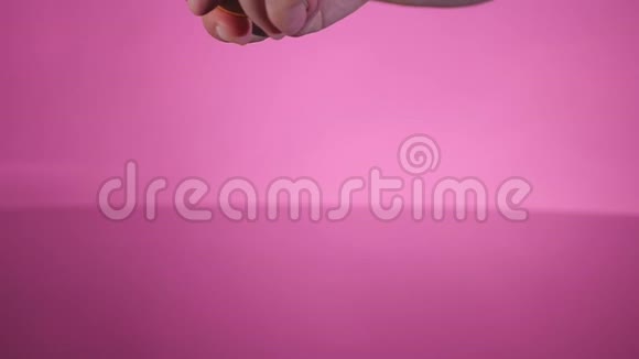 一个破鸡蛋掉在桌子上的粉红色背景上视频的预览图