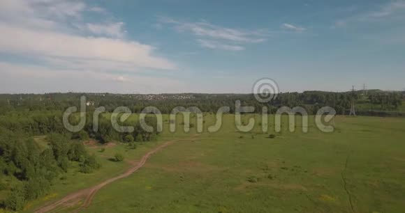 空中观景农村公路之间的农田和电力高压支架绿色田野之间的乡村道路4K视频的预览图