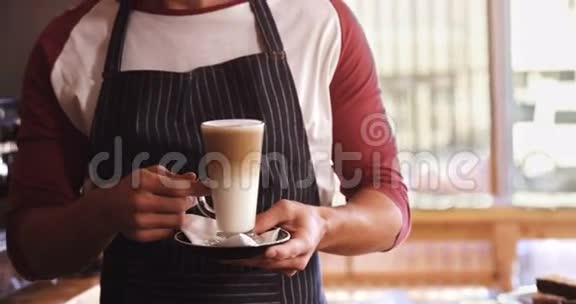 微笑的侍者拿着一杯冷咖啡在咖啡馆的柜台上视频的预览图