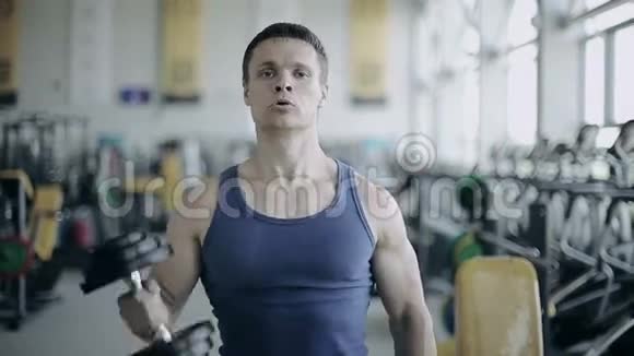 健美运动员在健身房用哑铃进行锻炼全脸射击视频的预览图