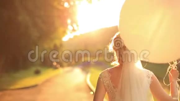 美丽的微笑新娘带着气球在秋天公园散步视频的预览图