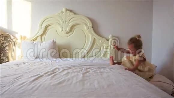 小女孩赌棍从白色床上跳到地板上的枕头视频的预览图
