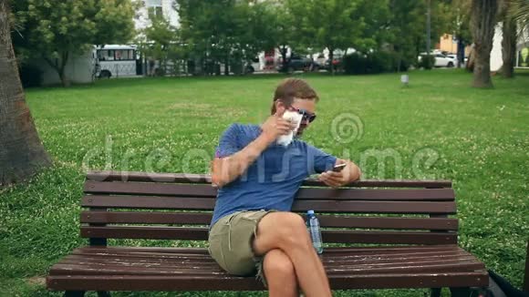 一个人坐在城市公园的长凳上由于炎热而精疲力竭视频的预览图