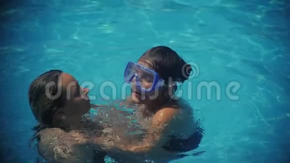 微笑着美丽的女人和她在游泳池里可爱的孩子一个幸福的家庭放松的肖像一起玩得开心视频的预览图