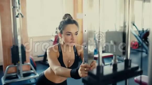 年轻漂亮的黑发女孩在健身房里留着长发在健身房4k视频上做运动视频的预览图