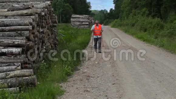 徒步旅行者在森林道路上用手杖走路视频的预览图
