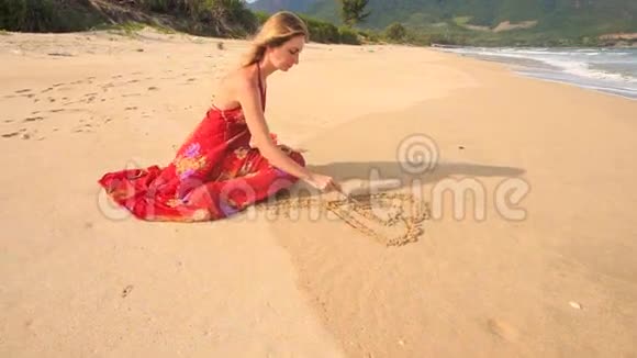 穿红衣服的女人在潮湿的沙滩上画心视频的预览图