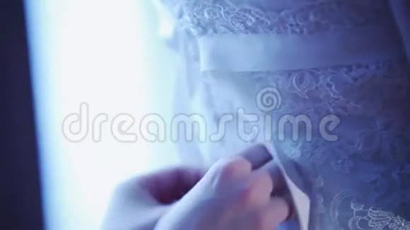 女人把丝带系在花边婚纱的背面给新娘庆祝日结婚平静的阴影视频的预览图