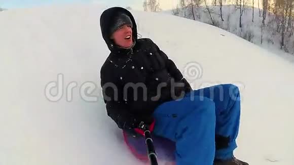 快乐的人骑着雪管在雪道上微笑慢动作冬天的雪景户外运动视频的预览图
