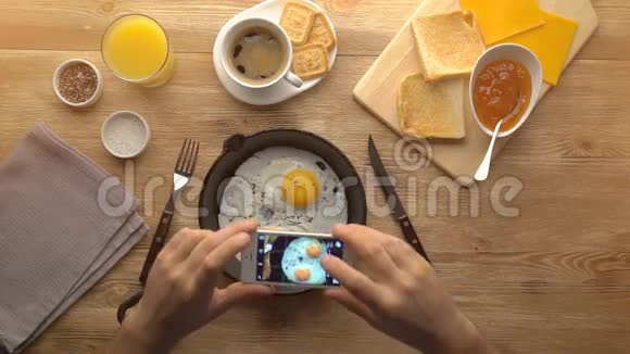 用手机拍照煎蛋男性手中的电话顶部视图视频的预览图