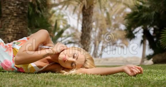 穿着太阳服的女人躺在草地上视频的预览图