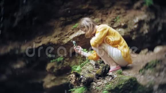 旅行冒险女在山上瀑布上拍摄智能手机欣赏大自然的美丽景色视频的预览图