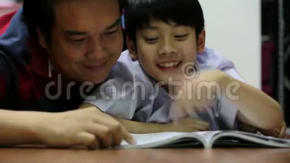 亚洲父亲和儿子一起读这本书视频的预览图