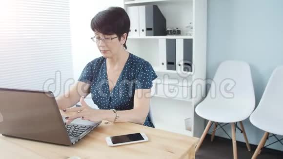 一位漂亮的中年女商人办公室里有一台笔记本电脑视频的预览图