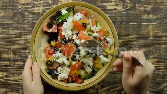 女性手在厨房里搅拌新鲜蔬菜沙拉和奶酪Feta蔬菜的混合特写视频的预览图
