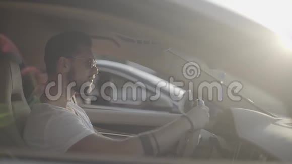 漂亮的纹身青年男子戴着太阳镜坐在豪华跑车对面准备开始比赛视频的预览图
