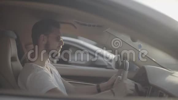 迷人的年轻纹身帅哥戴着太阳镜坐在豪华跑车对面的对手准备开始视频的预览图