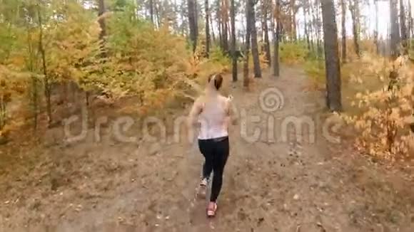 在秋季公园慢跑的快乐微笑女人慢动作视频的预览图