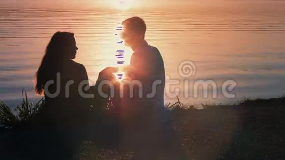 一对年轻夫妇在海滩接吻的剪影视频的预览图