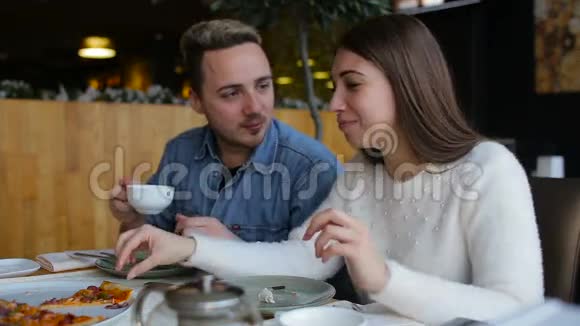 在城里的咖啡馆里聊天和吃披萨的夫妇视频的预览图