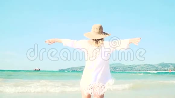 带着帽子和白色长袍的年轻金发女子在泰国海滩上活动视频的预览图
