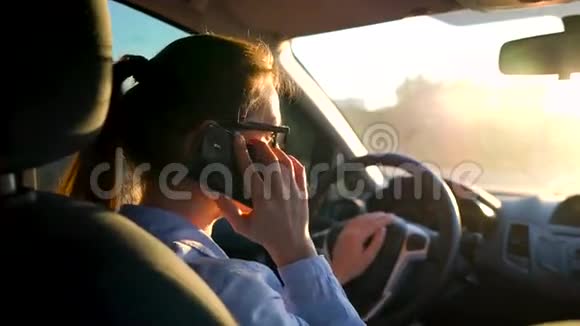 戴眼镜的女人在车里用智能手机说话视频的预览图