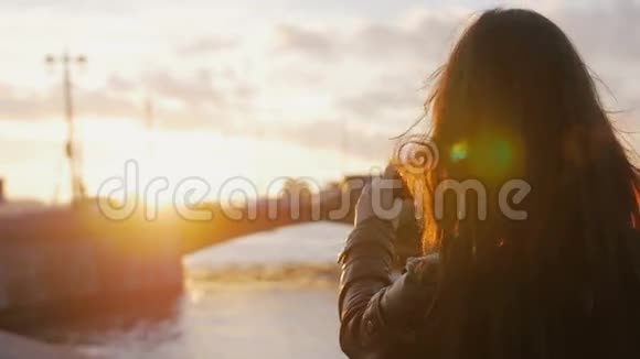 年轻漂亮的女孩在夕阳的明亮光线下制作了一张桥的智能手机照片4K视频的预览图