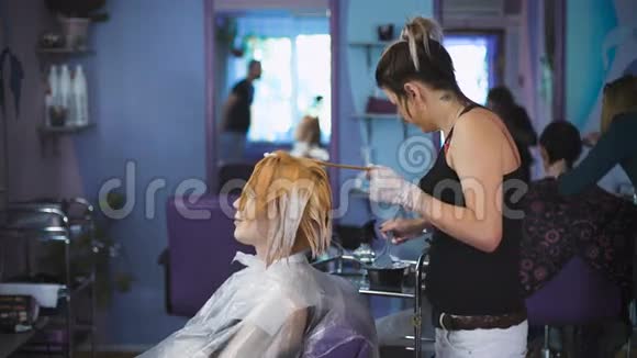 发型师理发师在他的客户的头发上做专业的油漆视频的预览图