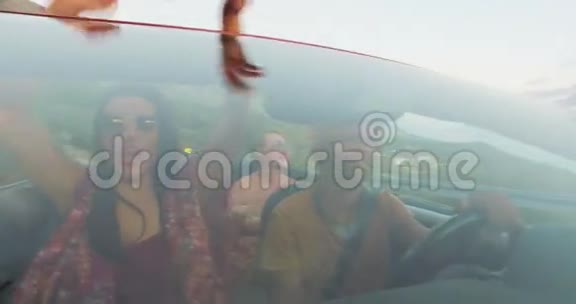 年轻的多民族朋友乘坐红色敞篷车的前景视频的预览图
