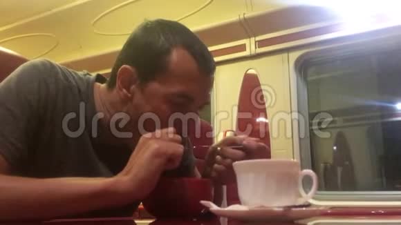 男人晚上在火车餐厅吃汤铁路生活方式猫喝咖啡火车上的人概念之旅视频的预览图