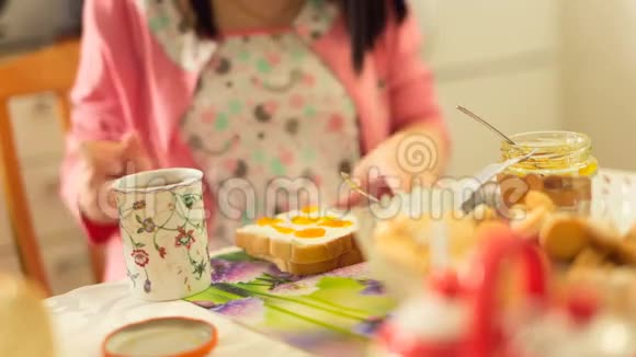 年轻的女人吃早餐喝茶视频的预览图