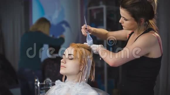 发型师理发师在他的客户的头发上做专业的油漆视频的预览图