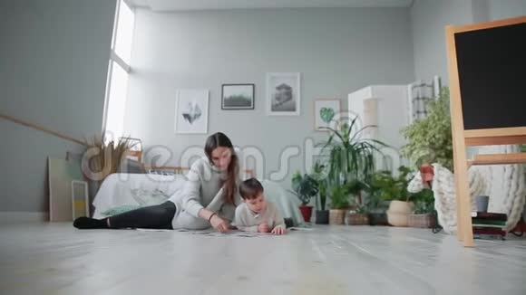 妈妈带着一个孩子在他家白色的内部和他的小儿子一起收集拼图快乐视频的预览图