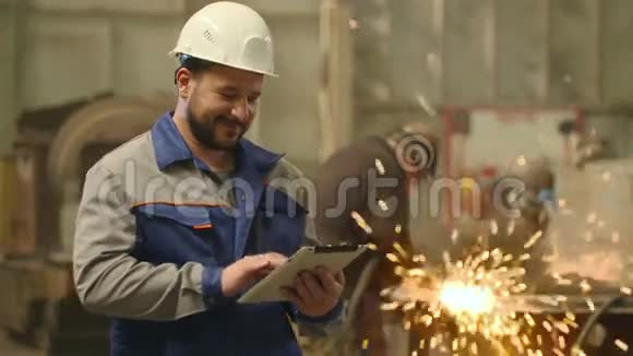 在重工业工厂里工程师看着摄像机微笑着举起大拇指视频的预览图
