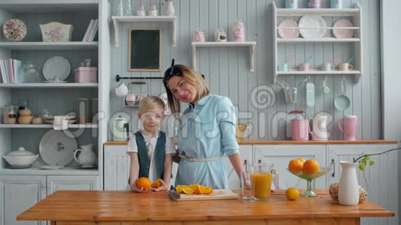 健康的人小男孩和小妈妈早上在厨房里做新鲜橙汁视频的预览图