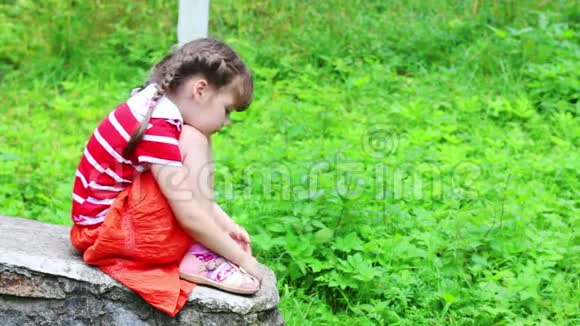 穿裙子的悲伤小女孩坐在石头上视频的预览图