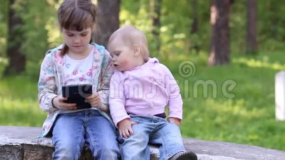 小女孩玩平板电脑其他小女孩看着它视频的预览图