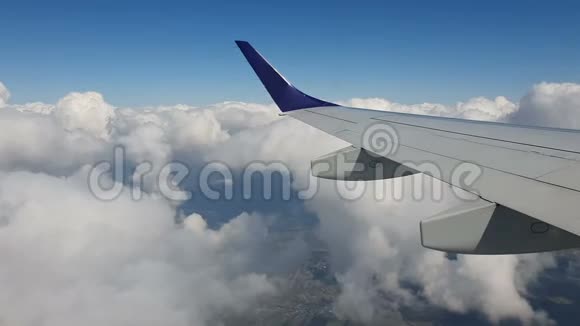 通过飞机的窗口查看飞机的机翼顶着蓝天白云背景视频的预览图