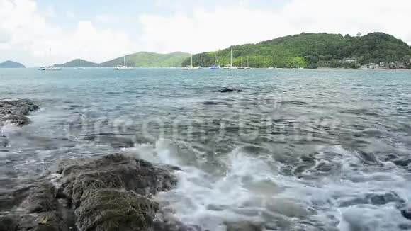 敖延海滩的海岸线风光低角度的海浪冲刷在岩石上安达曼海与游艇视频的预览图