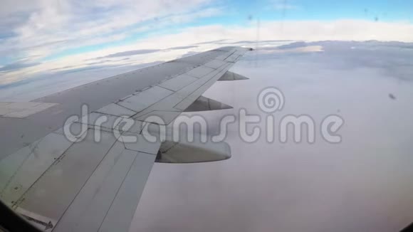 一架客机在云层上方低空飞行的机翼上的窗口视图视频的预览图