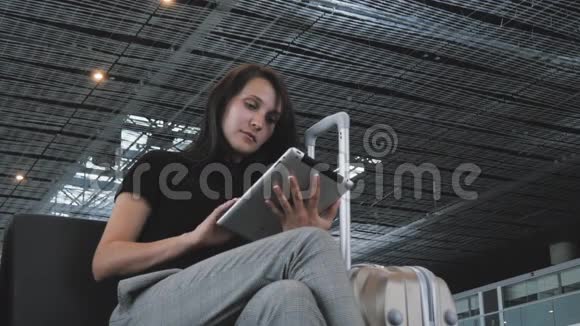 年轻漂亮的女商人在机场使用平板电脑等待排队登记旅行的概念视频的预览图