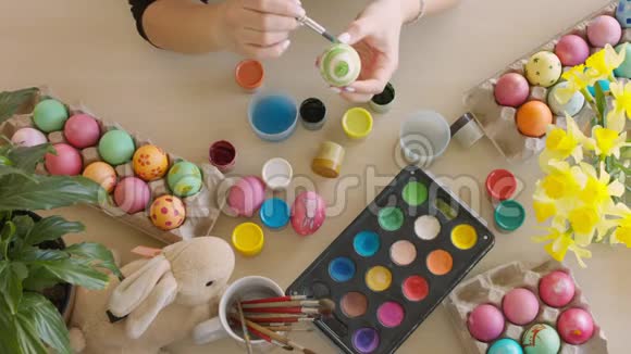 桌上放着五颜六色的复活节彩蛋女人用刷子给复活节彩蛋视频的预览图