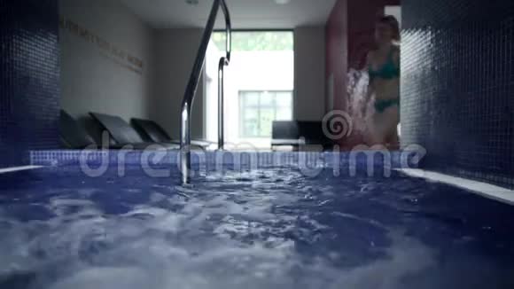 穿着蓝色比基尼的年轻女子在游泳池里放松视频的预览图