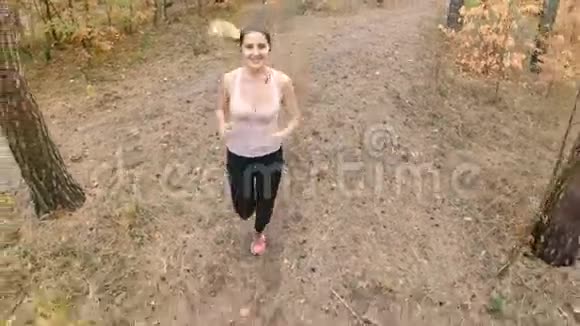 一段美丽微笑的女人在森林里奔跑的慢镜头视频的预览图